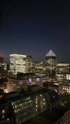 the city skyline is lit up at night with buildings in the foreground and lights on