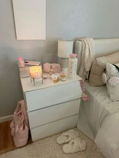 a bedroom with white furniture and pink accessories on the dresser next to it is lit by a candle