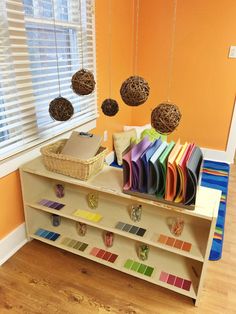 there is a book shelf with many books on it and hanging decorations in front of the window