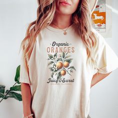 Elevate your style with this Organic Oranges Graphic T-Shirt featuring a vintage fruit design. Perfect for lovers of juicy and sweet Oranges, this tee carries a nostalgic look and celebrates Redlands, California. Ideal for casual outings, this shirt adds a unique touch to your wardrobe and showcases your love for fresh, organic produce. A great gift for fruit enthusiasts and those who appreciate retro designs. Available in various sizes and colors to suit your preferences. Product Features: Fabrication: Medium fabric (6.1 oz/yd² (206.8 g/m. Garment-dyed fabric. 100% ring-spun cotton Fit: Relaxed fit Sizing: Unisex Sizing Label: Sewn-in twill label Organic Short Sleeve T-shirt For Spring, Casual Orange Fruit Print Top, Organic White Crew Neck T-shirt, Organic Short Sleeve T-shirt With Screen Print, Vintage Fruit Print Top For Summer, Vintage Summer Top With Fruit Print, Vintage Orange Short Sleeve T-shirt, Graphic Tee With Fruit Design In Cotton, Organic Graphic Print T-shirt For Spring