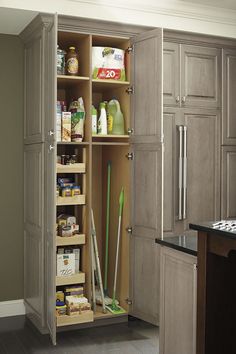 an open cabinet in a kitchen with cleaning supplies on the shelf and other items inside