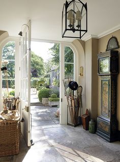 the inside of a house with an open door and large clock on the front porch