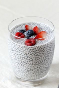 a bowl of chia pudding with berries and blueberries in the middle on a white surface