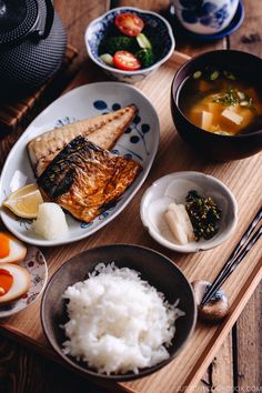 a wooden table topped with plates and bowls filled with food