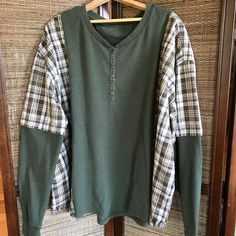 a green shirt with plaid sleeves hanging on a wooden hanger in front of a door