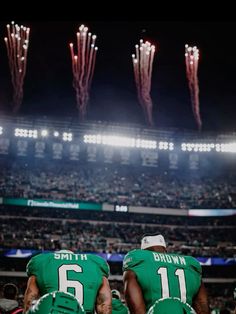 two football players sitting on the sidelines watching fireworks