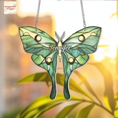 a green butterfly hanging from a chain with the word jenny on it's wings