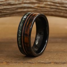 a wooden ring with black and green inlays on it sitting on a table