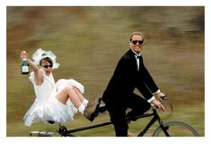 a man and woman dressed in white riding on a bike