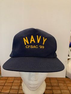 the navy hat is on top of a mannequin's head in front of a wall