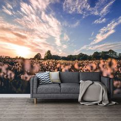 a couch sitting in front of a wall with flowers on it and a sky background