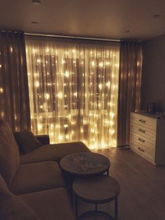 a living room with lights on the curtains and a couch in front of a window