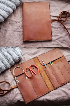 a pair of scissors sitting on top of a piece of leather next to some knitting needles