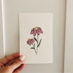 a hand holding up a piece of paper with flowers painted on the inside of it