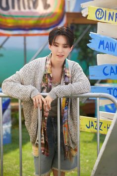 a young man leaning on a metal fence