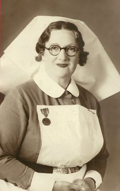 an old black and white photo of a woman wearing glasses with a apron over her shoulder