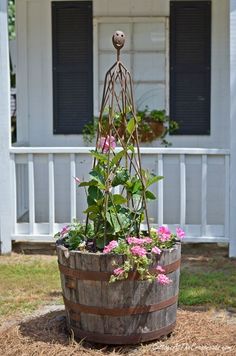 a wooden barrel filled with flowers in front of a house