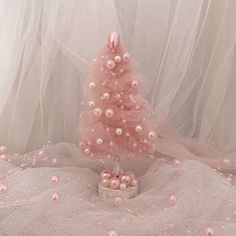 a small pink christmas tree sitting on top of a bed