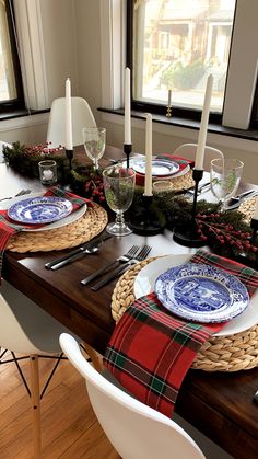 the table is set for christmas dinner with plaid napkins and place settings on it