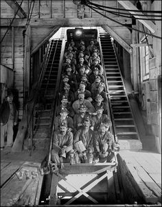 an old black and white photo of men riding on a roller coaster in a factory