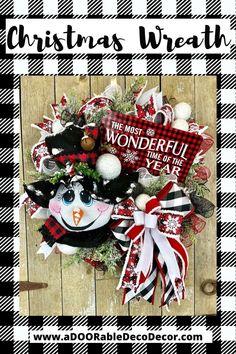 a christmas wreath with snowmen and ornaments hanging on a wooden wall next to scissors