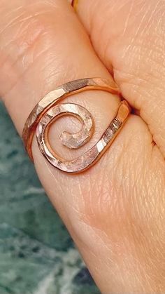 a woman's hand with a ring on it that has a spiral design in the middle