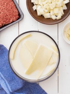 ingredients to make hamburger patties laid out on a white wooden table with blue towels