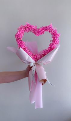 a person holding a pink heart shaped bouquet