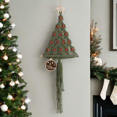 a christmas tree clock hanging on the wall next to a decorated christmas tree and stockings