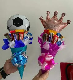 two hands holding candy bouquets with soccer balls and foil wrappers on the top