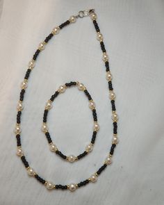 a black and white beaded necklace with pearls on it's end is shown