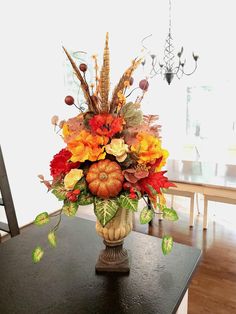 a vase filled with lots of colorful flowers on top of a wooden table next to a chandelier