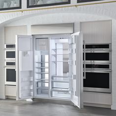 an open refrigerator with its doors wide open in a kitchen area that has white walls and gray flooring