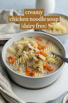 two bowls of creamy chicken noodle soup on a white plate with a blue towel