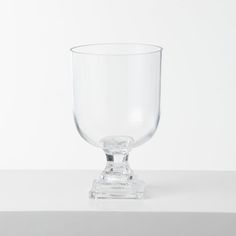 a clear glass cup sitting on top of a table next to a white wall and floor