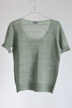 a green sweater hanging on a hanger against a white wall, with the top half open