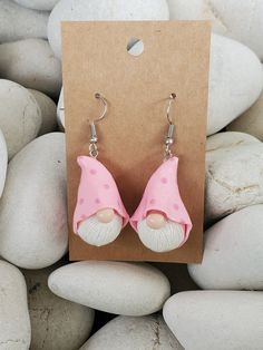 a pair of pink and white mushroom earrings sitting on top of some rocks next to each other