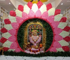 an elaborately decorated wall with flowers and a statue in the center is surrounded by greenery