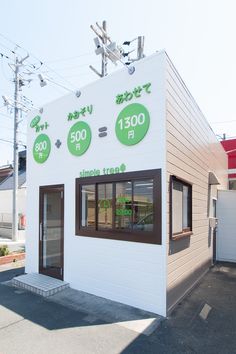 a small white building with some green signs on it's side and two windows