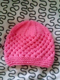 a pink knitted hat laying on top of a bed