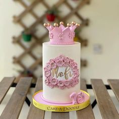 a cake decorated with pink flowers and a monogrammed crown is sitting on a table