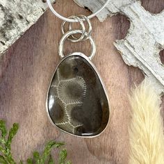 Petoskey Stone from Michigan, handcrafted into a cabochon and set in a custom, Sterling Silver bezel setting. Includes an 18 inch, solid sterling silver 1.1mm snake chain with clasp. The stone measures approximately 0.9 x 1.1 inches.  Overall pendant height is approximately 1.5 inches. The name Petoskey appears to have originated late in the 18th century.  Its roots stem from an Ottawa Native American legend. In 1965, the Petoskey Stone became the state stone of Michigan. Petoskey stone helps us Untreated Sterling Silver Round Pendant, Sterling Silver Rectangular Pendant With Lobster Clasp, Sterling Silver Rectangular Pendant Jewelry With Lobster Clasp, Sterling Silver Jewelry With Lobster Clasp And Rectangular Pendant, Sterling Silver Pendant With Bezel Setting, Sterling Silver Pendant Jewelry With Bezel Setting, Sterling Silver Pendant Necklace With Bezel Setting, Sterling Silver Cabochon Rectangular Pendant, Sterling Silver Cabochon Rectangular Pendant Jewelry