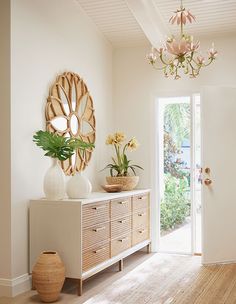 a living room with white walls and wooden floors, a large mirror on the wall