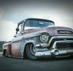 an old, rusty truck is parked on the street