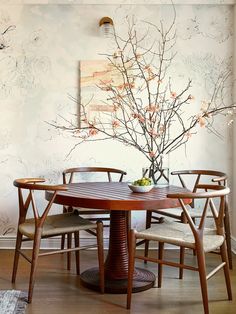 a dining room table with four chairs and a vase filled with flowers on the table