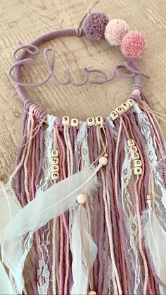 a pink and white crochet dream catcher on a wooden floor with the word love spelled out