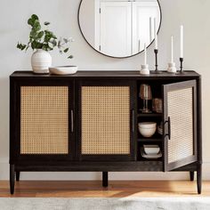 a wooden sideboard with wicker doors and mirror on the wall next to it