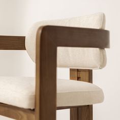 a close up of a wooden chair with white fabric on the back and seat cushion