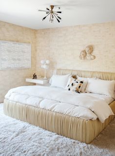 a large bed sitting in the middle of a bedroom next to a wall mounted fan