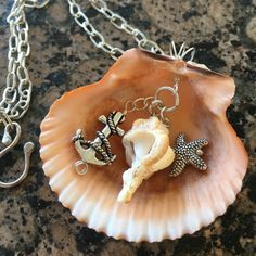 a seashell with two charms on it sitting on a table next to a chain